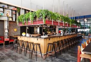 un restaurante con bar con taburetes y plantas en citizenM Washington DC NoMa en Washington