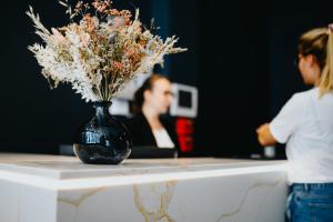 uma mulher sentada à mesa com um vaso de flores em Keystone Boutique Hôtel em Lyon