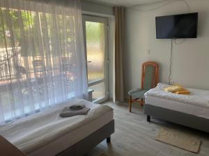 a bedroom with two beds and a tv and a window at Villa Bartosz in Międzywodzie +29 photos