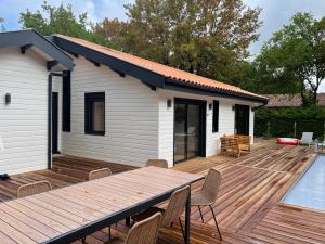 una terraza de madera con una casa y una piscina en Cap Ferret - Villa Sérénité - piscine, proche Océan et Bassin, classée 4 étoiles Meublé de tourisme, en Lège-Cap-Ferret