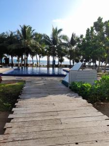 a walkway next to a swimming pool with palm trees at Apartment314 Oceanfront condos Nilaveli in Trincomalee
