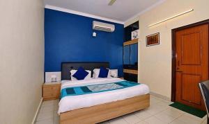 a blue bedroom with a large bed with blue walls at FabExpress Central Park in Dehradun