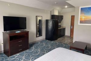 a hotel room with a bed and a flat screen tv at Days Inn & Suites by Wyndham Cleburne TX in Cleburne