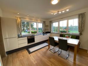 a kitchen with a table and chairs and windows at Residence JORADO in Manning