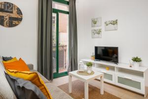 a living room with a couch and a tv and a table at Lodging Apartments Liceu G2 in Barcelona