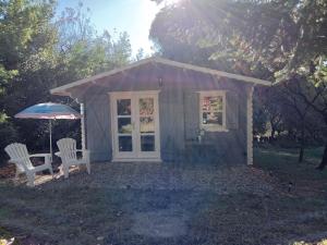 a small shed with two chairs and an umbrella at Chalet Le Petit olivier , gite l Echapée Belle Aubenas in Aubenas