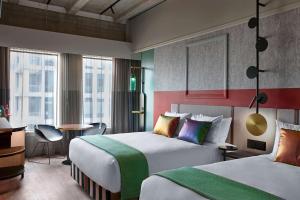 a hotel room with two beds and a desk at QT Auckland in Auckland