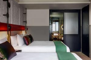 a hotel room with two beds and a desk at QT Auckland in Auckland