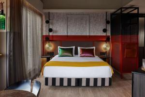 a bedroom with a large bed and a red wall at QT Auckland in Auckland