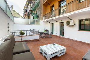 eine Terrasse mit einem Sofa und einem Tisch in einem Gebäude in der Unterkunft Lodging Apartments Liceu 11 in Barcelona