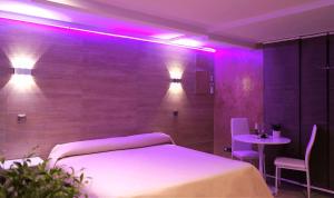 Cette chambre comprend un lit et une table avec des lumières violettes. dans l'établissement Caballero Errante, à Madrid