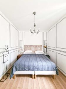 a white bedroom with a bed and a chandelier at Via Vittoria Quattro in Rome