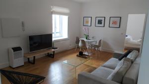 ein Wohnzimmer mit einem Sofa, einem TV und einem Tisch in der Unterkunft La Suite 57 in Capbreton