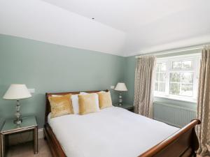 a bedroom with a large bed and two windows at Gardeners Cottage in Hungerford