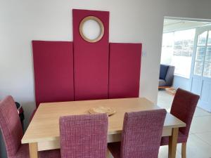 d'une salle à manger avec une table et un mur violet. dans l'établissement Castle Gardens Bungalow, Saint Helens Resort, Wexford - 3 Bedroom Sleeps 6, à Ballygerry