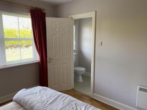 a bedroom with a bed and a bathroom with a toilet at Castle Gardens Bungalow, Saint Helens Resort, Wexford - 3 Bedroom Sleeps 6 in Ballygerry