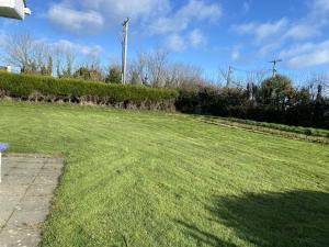 a large grassy field with a bench in a yard at Castle Gardens Bungalow, Saint Helens Resort, Wexford - 3 Bedroom Sleeps 6 in Ballygerry
