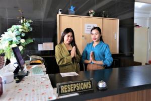 two women standing behind a counter in a room at Gading Guest House in Mataram
