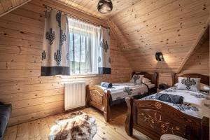 1 dormitorio con 2 camas en una cabaña de madera en Domki Górskie Janosik, Kwicoł i Pyzdra en Gliczarów