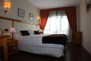 a bedroom with a bed, chair, lamp and window at Hotel Meta in Pas de la Casa