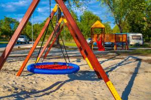 a swing set in a park with a playground at Zsóry Liget Camping & Resort in Mezőkövesd