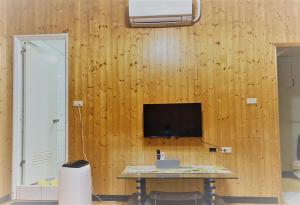 Pokój ze stołem i telewizorem na drewnianej ścianie w obiekcie Together Stay w mieście Juguang