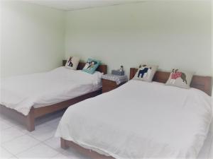 2 camas en una habitación con sábanas y almohadas blancas en Together Stay, en Juguang