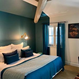 a bedroom with a bed with blue walls and a window at La Maison Sur La Sorgue - Esprit de France in LʼIsle-sur-la-Sorgue