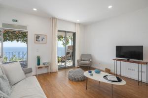 a living room with a couch and a tv and a table at Lazareto Mar by An Island Apart in Funchal