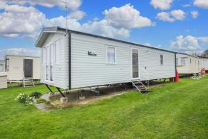 a large white mobile home in a yard at Beautiful 6 Berth Caravan For Hire At Central Beach Park In Kent Ref 57018b in Leysdown-on-Sea