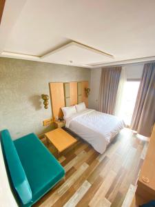 a bedroom with a bed and a blue chair at Hotel Atlantis Mazagan in Douar Draoud