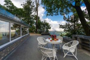 une terrasse avec une table et des chaises dans une maison dans l'établissement StayVista at Springfield with Scenic Lawn, à Kasauli