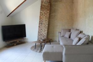 a living room with a couch and a flat screen tv at Superbe Appartement Circuit des 3 Chateaux in Folembray