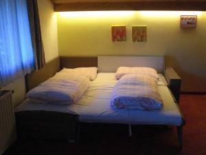a bed with two pillows on it in a room at Hotel-Pension Flora in Saalbach Hinterglemm