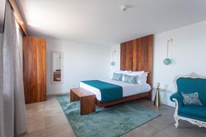 a bedroom with a bed and a blue chair at Casa dos Romeiros in Santa Bárbara