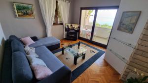 a living room with a blue couch and a table at Apartman Podgora with beautiful sea view in Podgora