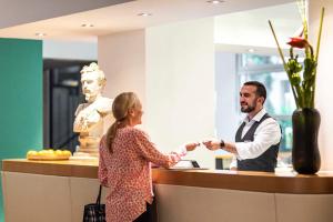 a man and a woman shaking hands at a counter at Boutique Hotel Atrium München in Munich