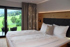 a bedroom with a large white bed with a large window at Bergzauber Alpin Suites - Skipiste - Private Sauna in Bolsterlang
