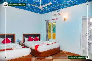 two beds in a room with blue ceilings and red pillows at Hotel Greenland Safari in Sauraha