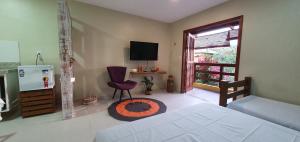 um quarto com uma cama, uma televisão e uma cadeira em Quintal da Espera - Praia de Itacimirim em Camaçari