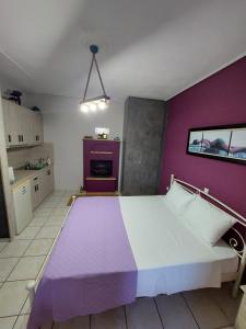 uma cama grande num quarto com uma parede roxa em Alesta Apartment em Trikala