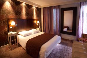 ヴァランスにあるHotel Les Negociantsの大きなベッドと鏡が備わるホテルルームです。