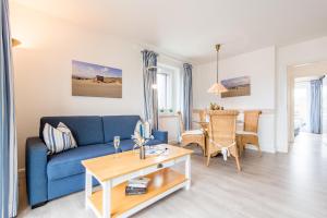 - un salon avec un canapé bleu et une table dans l'établissement Haus Hauke Whg 8, à Westerland