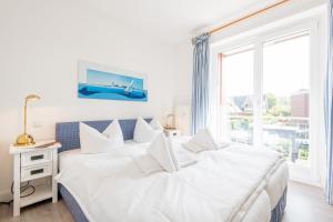 een witte slaapkamer met 2 bedden en een raam bij Haus Hauke Whg 8 in Westerland