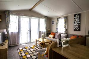 a living room with a couch and a table at Beautiful 6 Berth Caravan For Hire At Central Beach Park In Kent Ref 57018b in Leysdown-on-Sea