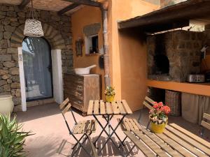 a patio with two benches and a table with flowers at Cactus b&b Le casette di Marilena in Pantelleria