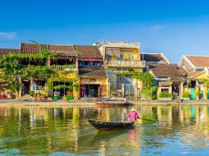 a person in a boat on the water in front of buildings at Two-Bedrooms - POOL SEA VIEW - 6A - BLUE SEA APARTMENT in Da Nang