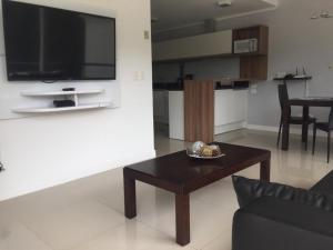 a living room with a table and a flat screen tv at Green Park in Punta del Este +5 photos