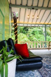 - un canapé en cuir noir avec un oreiller rouge sur une terrasse couverte dans l'établissement Villa Kamar Tamu Selomartani 2, à Sleman