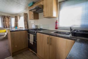 a kitchen with a sink and a stove top oven at Lovely Caravan With Free Wifi Nearby Great Yarmouth Seaside Town Ref 20085bs in Hopton on Sea